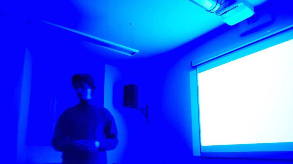 Immagine di una presentazione del cineforum: lo schermo blu del proiettore in standby irraggia il presentatore