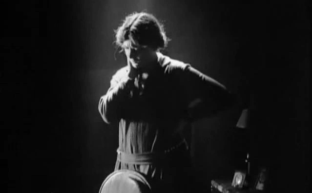 Immagine dal film La sorridente signora Beudet. Una donna in piedi, illuminata posteriormente dalla luce